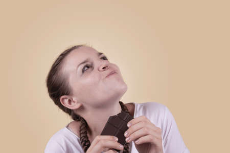 The girl tastes chocolate. The girl is enjoying the taste of chocolate.の写真素材
