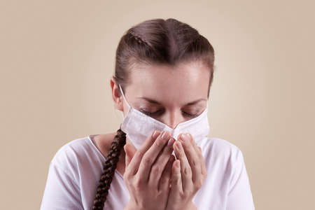 Girl in a medical mask. Girl on a yellow background. The girl sneezes, coughs.の写真素材