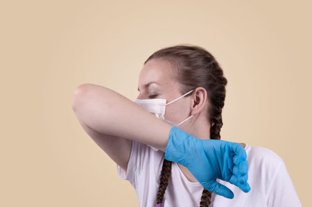 Girl in a medical mask and gloves. Girl on a yellow background. The girl is protecting herself from...
