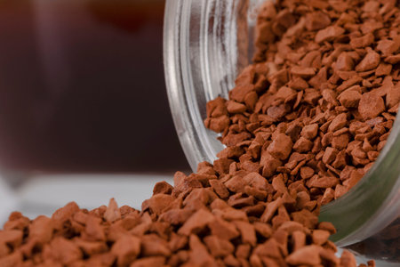 Instant coffee granules lying on the surface. Kofk granules spilled out of the jar lying on the...