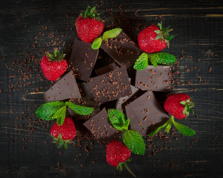A beautiful still life of dark chocolate, juicy strawberries and green mint leaves.の写真素材