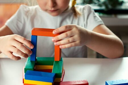 little blond girl playing board games. board games concept. wooden builing blocks in girl's hands. kids leisure project.の写真素材
