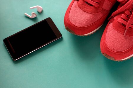 Generation Z and young people concept. black modern smartphone, red sneakers and wireless earphones on trendy background. の写真素材