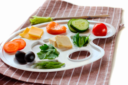 palette with colorful vegetables, fish and greens, creative food design, funny and healthy meal for...
