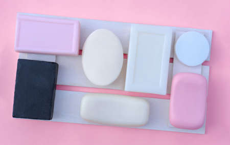 pink, white and black soap bars on a wooden tray. personal hygiene and face skin cleansing concept. variety of shapes of solid soap. fragranced soap.の写真素材