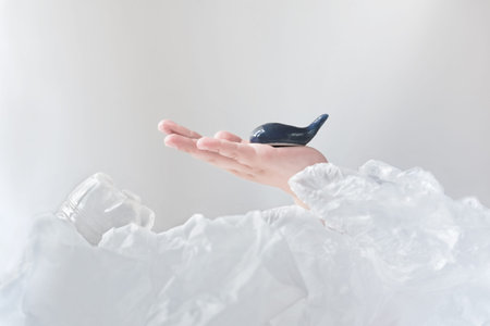 baby's hand holding blue whale saving from plastic waste. toy whale in girl's hands. sea life protection, ocean waste reduction. Plastic pollution creative concept advertise for campaign save oceansの写真素材
