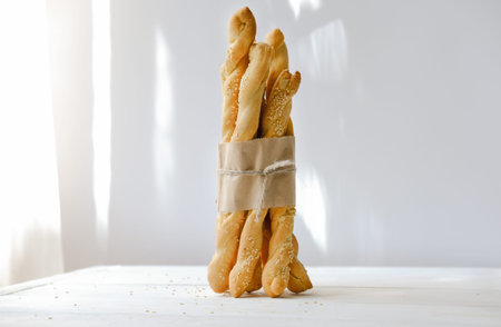Italian grissini or salted breadsticks. sesame breadsticks in a craft paper on white wooden table....