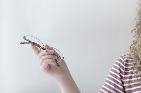 young woman's hand holding eyeglasses. eyesight care. gadgets damage concept. Female ophthalmologist...