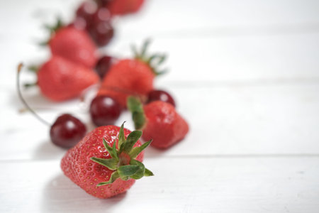 fresh summer berries on a white wooden table. strawberries and cherry, close up view. copy space for...
