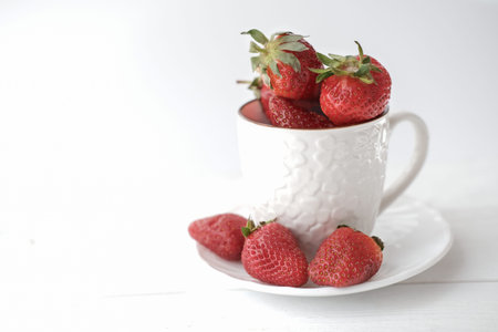 fresh strawberries in a white tea cup. summer berries. minimal style concept. copy space for text. vegetarian food concept.の写真素材