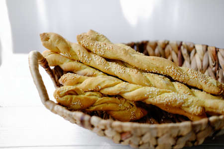 Italian grissini or salted breadsticks. sesame breadsticks in a craft paper on white wooden table. close up viewの写真素材