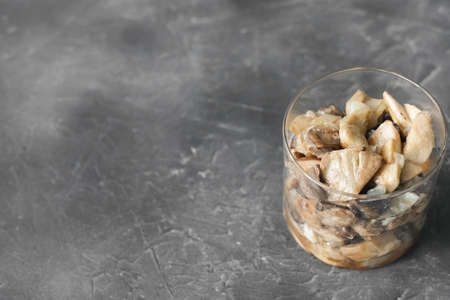 canned pickled forest mushrooms on a gray table. glass jar with mushrooms conserved for winter season. harvesting and preservation concept. high protein meal. open jar.の写真素材