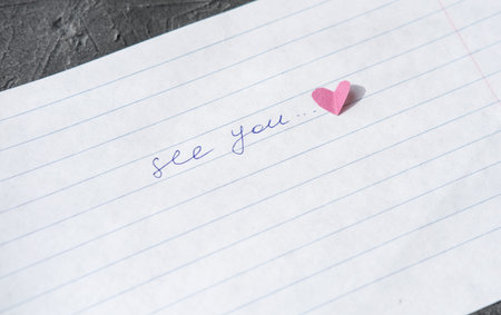 see you note hand written on a paper. love letter with paper heart. relationship concept. distance...
