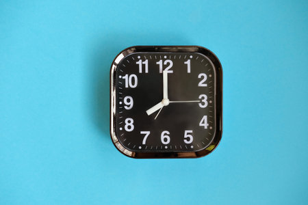 black modern alarm clock on blue background. good morning concept. wake up at eight o'clock