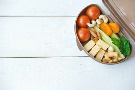 Back to school concept. Healthy lunch box with cheese, tomatoes, cocumber and nuts. school lunch for peacky eaters. copy space for textの写真素材
