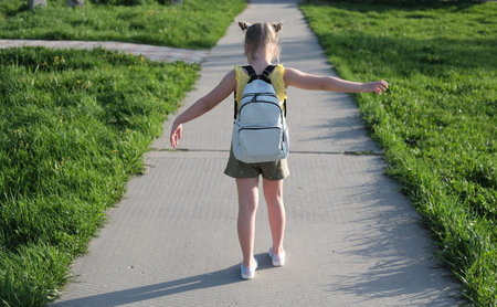 little cute girl goes to school. blonde girl with school bag and space buns hairdo. back to school concept. back view.の写真素材