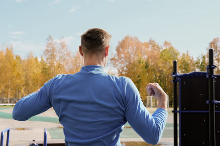 back view of a toned sporty man showing his muscules. autumn or fall stadium. sporty guy before...