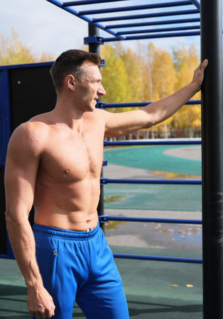 middle age shirtless man resting after outdoors workout. autumn season training. outdoors stadium....