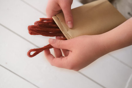 womans hand holding biltong or jerked meat. traditional south african dried meat. biltong strips in...