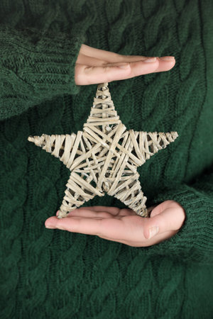 female hands holding eco christmas star. teenager girl wearing deep green pullover and holding star...