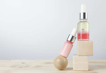 glass bottles droppers with anti age cosmetic oil on wooden pedestal. front view. copy space for text. serum for skin rejuvenation. collagen peptides cream.の写真素材