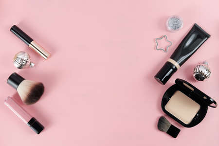 set with makeup products and Christmas decor on pink background. Space for text. holiday gift for women. lipstick, compact powder and shining balls. foundation and mascara.powder brush.の写真素材