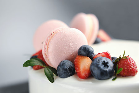 close up view of cake decorated with fresh strawberries, blueberries and macarons. french macaroons...