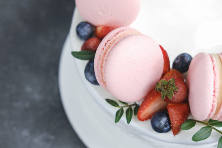 close up view of white cake decorated with french macarons.