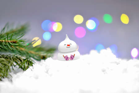 cute edible snowman on the snow and christmas tree branch. bokeh lights. holiday selebration and merry christmas, sugar candy snowman for cake top.の写真素材
