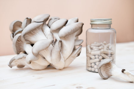 a bottle of mushroom supplement capsules and fresh mushrooms on a wooden table. antioxidant and detoxifying effect. alternative medicine concept, health treatment with vegan food,の写真素材