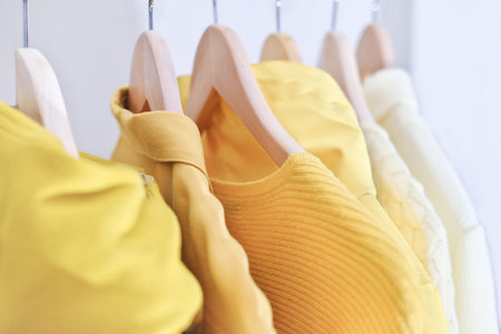 Feminine clothes in yellow color on hanger. Spring cleaning home wardrobe. Minimal fashion concept....