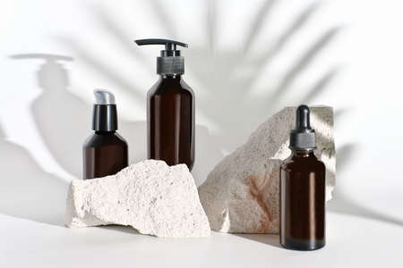 natural beauty care products in unbranded brown bottles. summer face care. moisturizing oils and lotions for dry skin. palm leaf shadow. mock up for your cosmetic brand.の写真素材