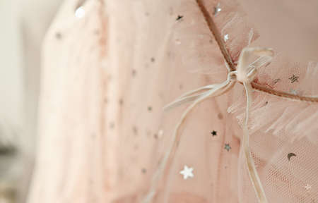 close up view of wedding dress in beige shades with stars. festive tulle dress for party and holiday selebration. light mesh fabric and gathers or folds. female clothes concept. selective focusの写真素材