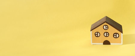 wooden toy house on a yellow background. banner size, house rental and loan. family living. countryside slow living concept.の写真素材