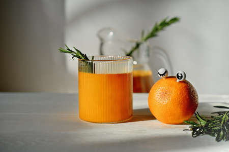 funny food concept. orange with eyes and orange juice for kids menu. rosemary leaves in a glass. healthy chidlren food and drinksの写真素材