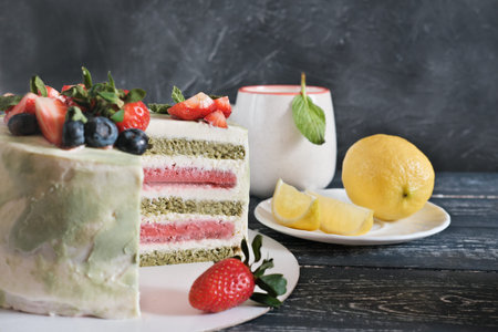 layered matcha and strawberry cake and a cup of tea with lemon and mint. birthday selebration. holiday food. vegetarian homemade cake with superfood ingredients.の写真素材