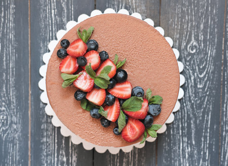 top view of a velvet chocolate cake baked for birthday or annivarsary selebration. fresh strawberry and blueberry decor with mint leavesの写真素材