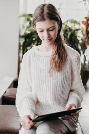 teenager girl looking at pc tablet sitting in a hall. vertical size. selective focus. toned photo portraitの写真素材