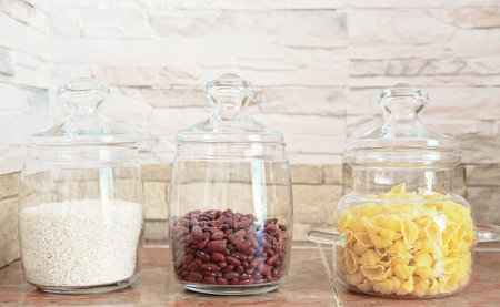 food storage and order in a kitchen. glass containers for grocery on a shelf. front view.