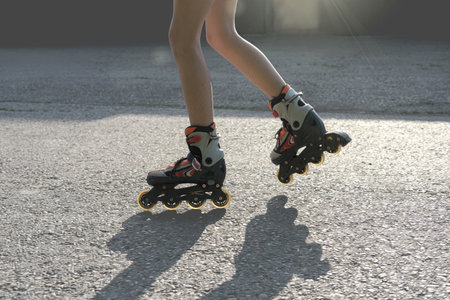 teenager girl's legs wearing roller skates. partial view. teen girl rollerblading in the street. leisure and summer activity.の写真素材