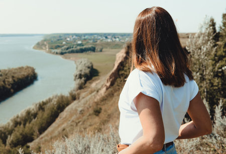 rear view of a young woman looking at autumn river landscape, local travel concept. beautiful and...