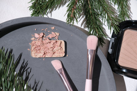 eyeshadows smash on a broken cement or concrete tray next to eyeshadow brushes and face powder....