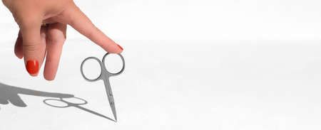 female hand touching nail scissors. manicure concept. nail care, beauty tools. banner sizeの写真素材