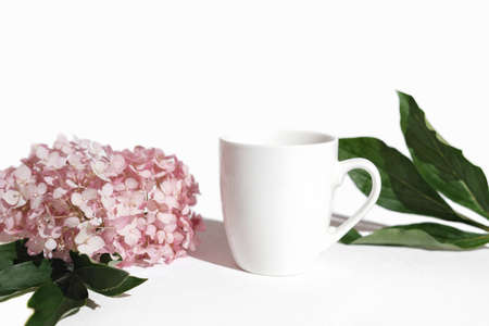 mockup tea mug, white cup for tea or coffee. template for your design. white background with pink flowers and green leavesの写真素材