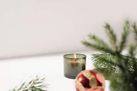green scented christmas candle next to pine branch and red christmas ball. copy space. holiday home decor. forest and pine scented candleの写真素材