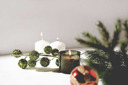 green scented christmas candle and white wax candles next to pine branch and red christmas ball. holiday selebration. forest and pine scented candle.の写真素材