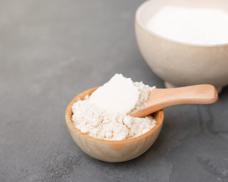 coconut flour in a wooden plate and a spoon. alternative flour for keto meal and LCHF diet....