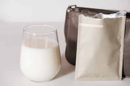 collagen powder travel pack and a glass of milk to make protein cocktail. collagen peptides powder for healthy drink. support for beautiful skin. lady's bag to take a protein sachet to go.の写真素材