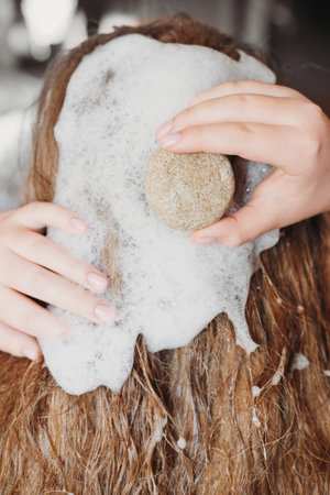 Young woman using natural eco friendly solid shampoo bar. Zero waste and sustainable plastic free...