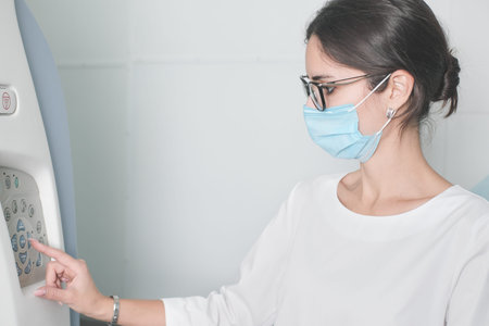 woman radiologist doctor adjusting computer tomography scanner machine to make CT test. female...